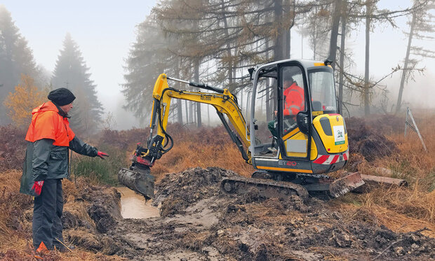 zwei Arbeiter mit Bagger im Moor