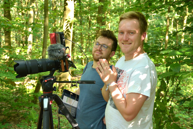 zwei junge Männer hinter einer Kamera im Wald