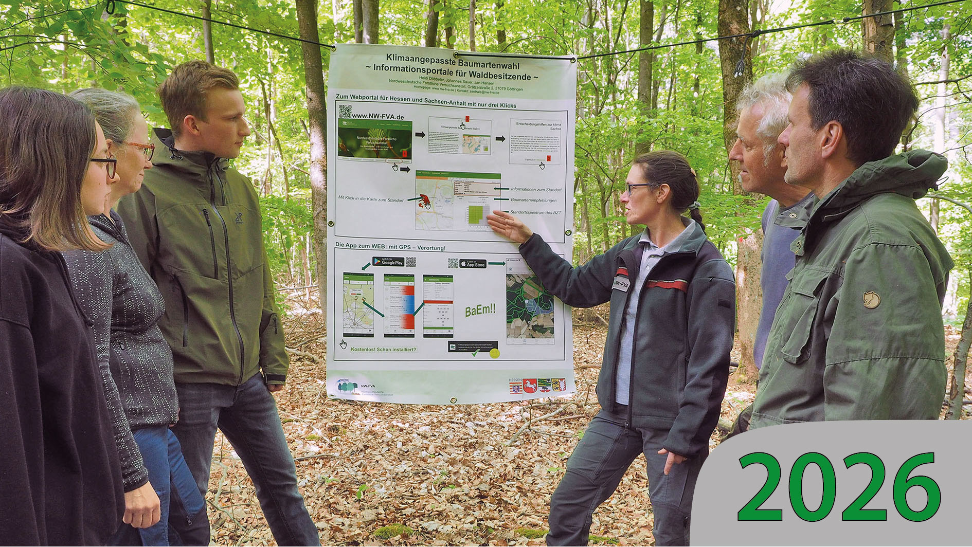 Gruppe im Wald bekommt die Baumartenempfehlungen vor einem Poster erklärt